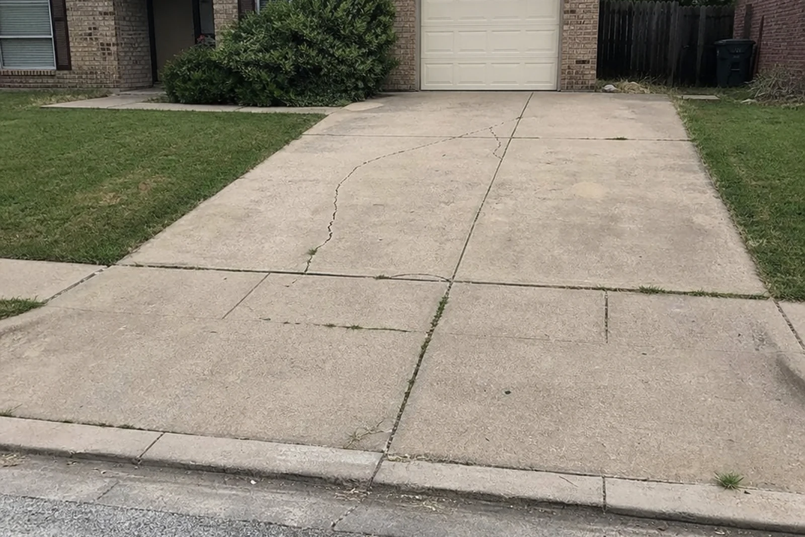 Realistic iPhone photo of Garland Texas residential concrete driveway estimate with curb apron and cracked panels