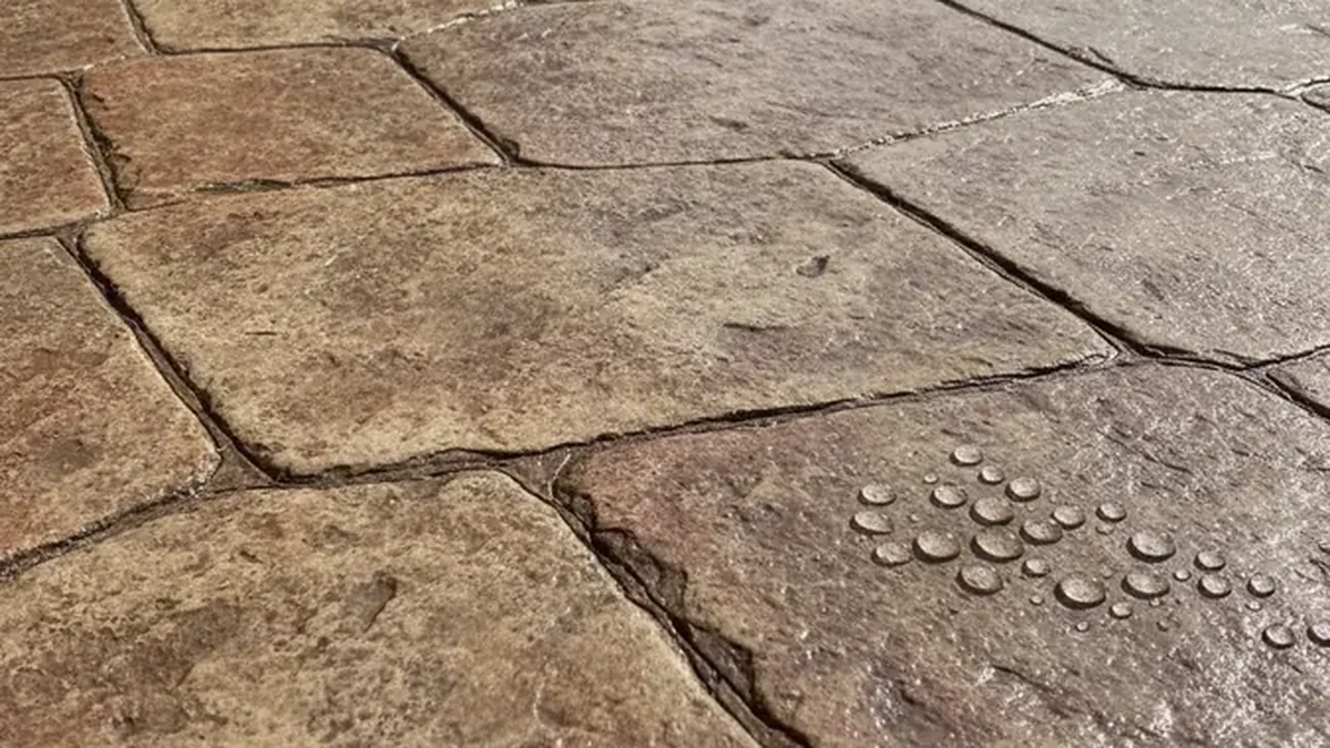 Sealer is applied across a clean stamped concrete surface to protect color from Texas sun.