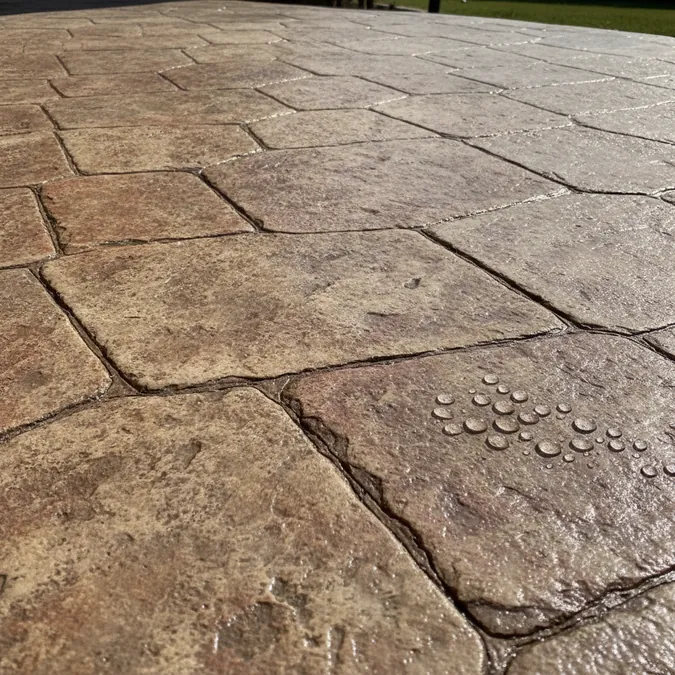 Sealer is applied across a clean stamped concrete surface to protect color from Texas sun.